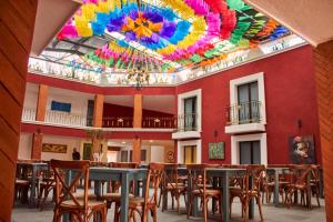 乔卢拉Hotel Casa Real Cholula的客房设有桌椅和色彩缤纷的天花板。