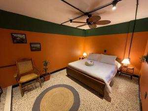布卡拉曼加La Bonita Guesthouse的一间卧室配有一张床、风扇和椅子