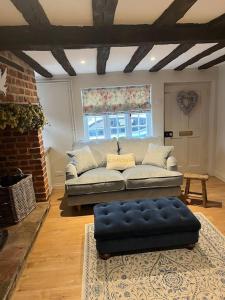 GodmanchesterHistoric Cambridgeshire Cottage的带沙发和蓝色搁脚凳的客厅