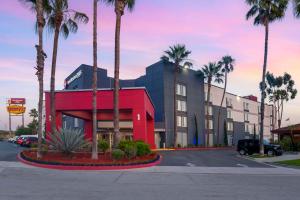 洛杉矶华美达商务酒店的停车场前方的棕榈树建筑