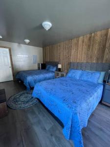加德纳ParkWay Yellowstone Guest House Room #1的卧室内的两张床,配有蓝色的棉被