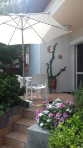 乔保克Csopak Mariann Apartman的一个带白色遮阳伞和一些鲜花的庭院
