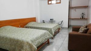 奥克萨潘帕Excelente ubicación! Bellas y cómodas habitaciones en el centro de Oxapampa的客房设有两张床、椅子和沙发。