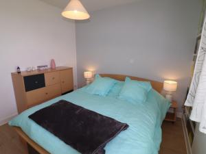 欧里亚克Appartement Aurillac, 2 pièces, 2 personnes - FR-1-742-389的一间卧室配有一张带蓝色床单的床和两盏灯。