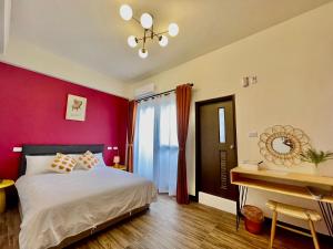 马公棉宝民宿的卧室设有红色墙壁、一张床和一张书桌