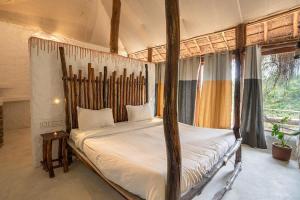 KanthalloorDeshadan Eco Valley Resort - An Eco friendly Mud House的一间卧室设有四柱床和窗户。