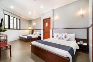 胡志明市Văn Hoa Hotel的酒店客房设有两张床和一张桌子。