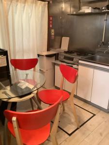 东京羽田机场旅馆的厨房配有2把红色椅子和玻璃桌
