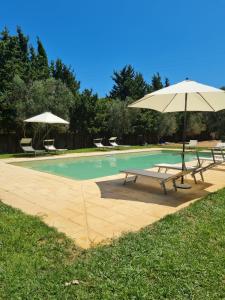 奥特朗托Masseria Fagà的一个带2个长椅和遮阳伞的游泳池