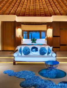 Fesdu Island马尔代夫W酒店的一间卧室配有一张带蓝色枕头的床和一张桌子