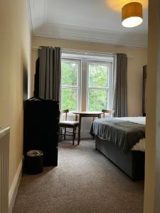 巴洛赫Norwood Guesthouse-Loch Lomond的卧室配有床、桌子和窗户。