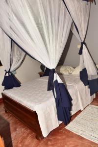 MadirokelyVilla ZAKIA的一间卧室配有两张带蓝白色窗帘的床