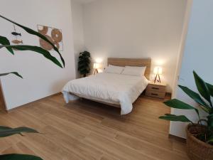 加拉夫Mi Casita De Garraf的一间白色的卧室,配有床和盆栽植物