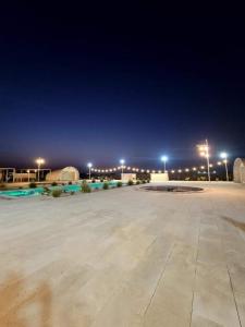Al ḨamrānīyahDesert Breeze Farm Resort的夜间大型停车场,有街灯