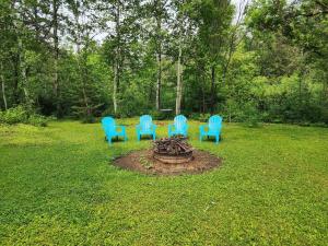 Little House by the Brook的院子里一个火坑周围四把蓝色椅子