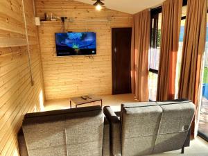 乌雷基House&Yard Hellen 150m to beach的客厅配有沙发和墙上的电视