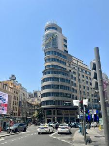 马德里米兰旅舍的一座大型建筑,前面有汽车停放