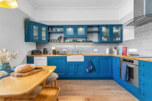 比加Beeswing, a Victorian Gem in Biggar的蓝色的厨房配有木桌和蓝色橱柜