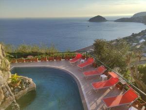 伊斯基亚Hotel Villa al Mare的一个带躺椅的游泳池和海洋