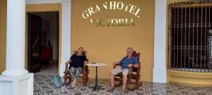里瓦斯GRAN HOTEL VICTORIA的两个女人坐在大楼前的摇椅上