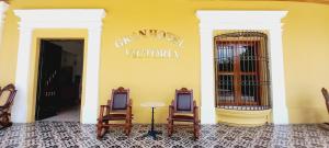 里瓦斯GRAN HOTEL VICTORIA的一间设有两把椅子和一张桌子的房间,还有黄色的墙壁