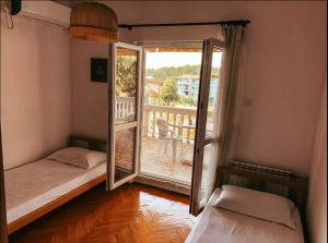 蒂瓦特Peaceful, Cosy Tivat Guesthouse的客房设有两张床和通往阳台的门。