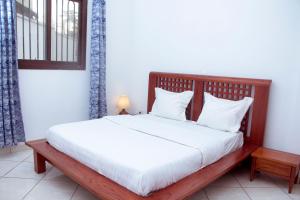 雅温得Résidence Vedette的一间卧室配有一张带白色床单和枕头的木制床。