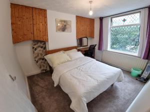 罗奇代尔4 Bedroom House in Central Rochdale cul-de-sac Free Parking & Fast Wi-Fi的卧室配有白色的床和窗户。