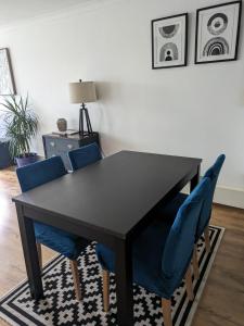 伦敦2 bed flat, Bounds Green, Piccadilly line, London N11的客厅配有一张带蓝色椅子的黑桌