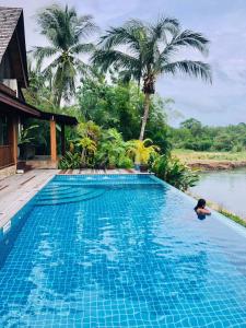 象岛Nanai Resort Salakphet的住在房子旁边的游泳池里的人