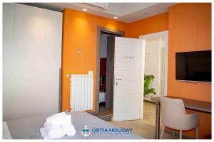 丽都迪奥斯蒂亚Ostia Holiday Sunset的一间设有橙色墙壁、桌子和电视的房间