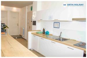 丽都迪奥斯蒂亚Ostia Holiday Sunset的厨房配有白色橱柜和水槽
