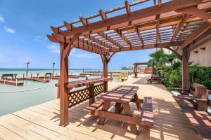 南帕诸岛Bayfront condo with water view & boat slips!的木甲板上设有野餐桌和长凳