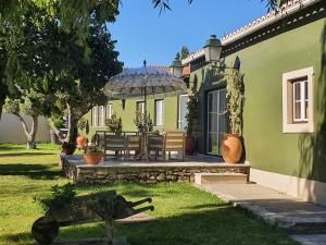 瓦尔杜德弗拉德斯Quinta do Pinheiro Hotel Rural - GQL的一个带长凳和遮阳伞的绿色房子
