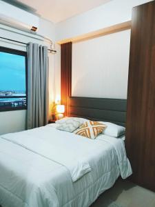 马尼拉2BR SMDC Bloom Residences Near NAIA Wi-fi +Netflix的卧室配有一张大白色床和窗户