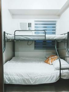 马尼拉2BR SMDC Bloom Residences Near NAIA Wi-fi +Netflix的配有白色床罩的客房内的双层床