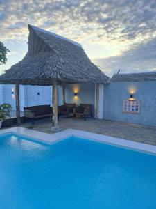 蒙巴萨Shany’s Villa 3bdrm with private swimming pool的一个带大遮阳伞和房子的游泳池