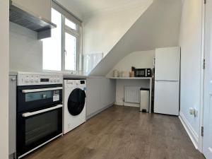 亨顿Stylish Modern, 1 Bed Flat, 15 Mins To Central London的厨房配有炉灶、洗衣机和烘干机