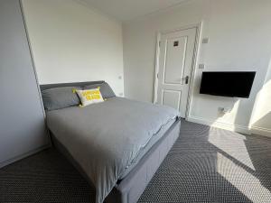 亨顿Stylish Modern, 1 Bed Flat, 15 Mins To Central London的一间卧室配有一张床和一台平面电视