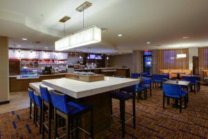 法明代尔长岛/法明代尔共和国机场万怡酒店的餐厅设有酒吧,酒吧配有蓝色酒吧凳子