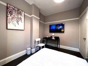 悉尼Coco’s Abode的一间卧室配有一张床、一张书桌和一台电视。