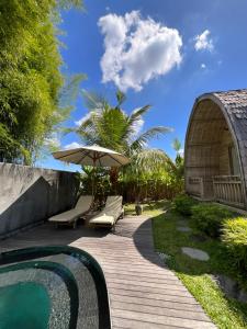 坎古Tanhana Villa Canggu的一个带遮阳伞和游泳池的木制走道