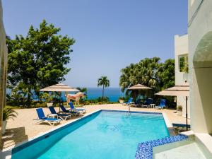 StruieHigh Life Resort & Spa的一个带椅子和遮阳伞的游泳池以及大海