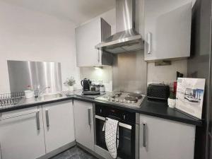 曼彻斯特Cityfront Modern Apt Near City Centre/Etihad, Free Parking的厨房配有白色橱柜和炉灶烤箱。