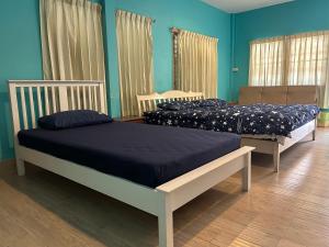 华欣ThaiTae GuestHouse HuaHin的蓝色墙壁客房的两张床