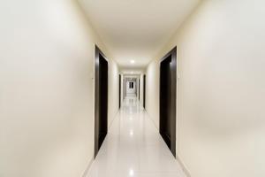 GunadalaHotel CJ Inn的走廊设有黑色门和白色瓷砖地板
