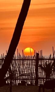 贝鲁沃勒CocoVilla Boutique Resort的海滩上的日落,太阳在围栏后面