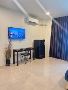 Ban Thung ThongAB House的一间设有桌子和墙上电视的房间