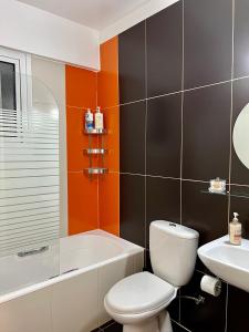 拉纳卡Fat Cow Apartment 01的浴室配有卫生间、浴缸和水槽。