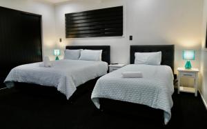 罗托鲁瓦A Dreamed Home Away From Home的一间卧室配有两张带白色床单和蓝色灯具的床。